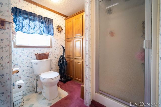 bathroom with a textured ceiling, a stall shower, toilet, and wallpapered walls