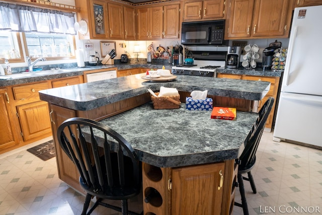 kitchen with white appliances, a kitchen breakfast bar, a center island, light floors, and a sink