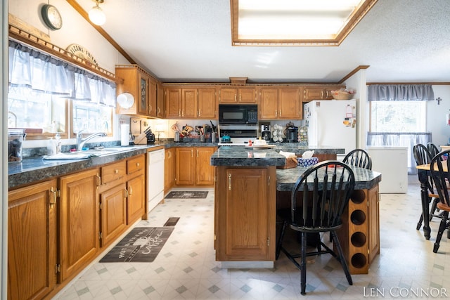 kitchen with brown cabinetry, a center island, white appliances, and light floors