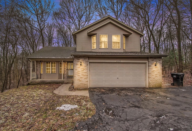 view of front of property with a porch, brick siding, a garage, and aphalt driveway