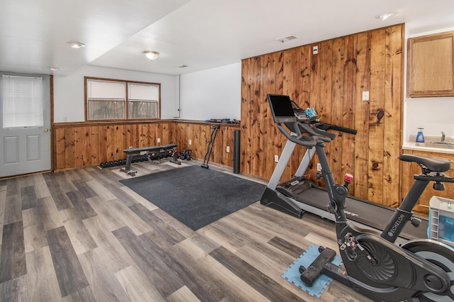 workout room with a wainscoted wall, wooden walls, visible vents, and wood finished floors