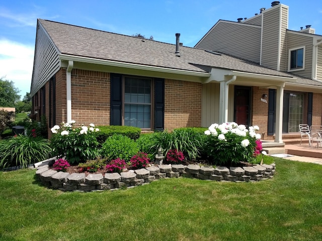 exterior space with a yard, brick siding, and roof with shingles