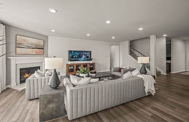 living area with baseboards, stairway, recessed lighting, a fireplace, and light wood-style floors