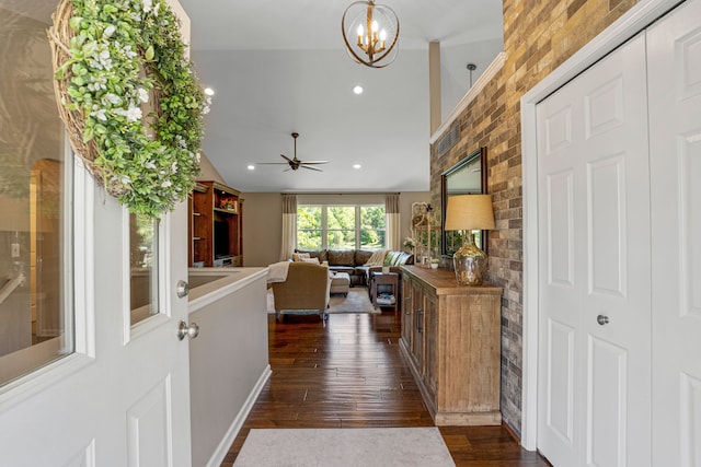 entryway with ceiling fan with notable chandelier, dark wood-style floors, recessed lighting, brick wall, and lofted ceiling