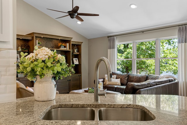 kitchen featuring a sink, open shelves, light stone counters, recessed lighting, and vaulted ceiling