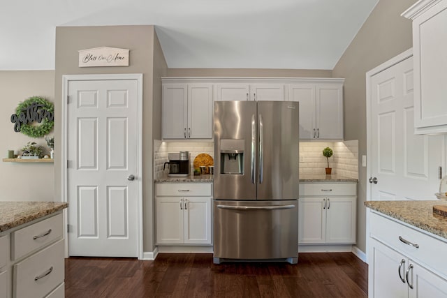 kitchen with stainless steel fridge, white cabinets, dark wood-type flooring, and light stone countertops