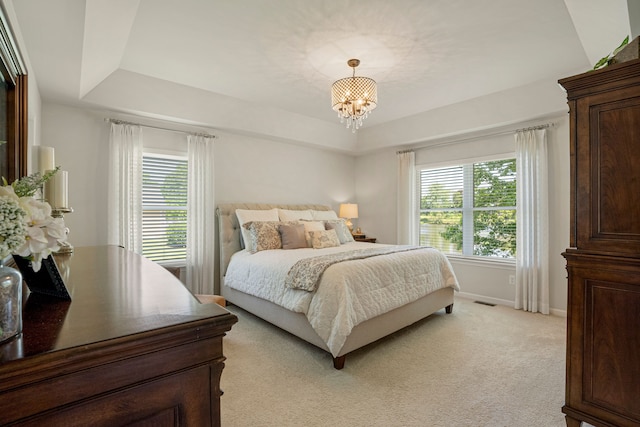 bedroom with a tray ceiling, light carpet, and multiple windows