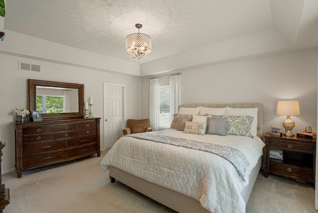 bedroom with a tray ceiling, visible vents, and light carpet