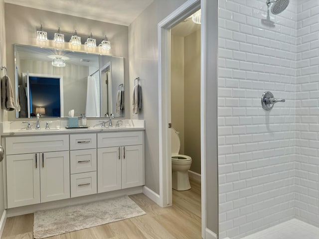 full bathroom featuring a sink, tiled shower, toilet, and wood finished floors