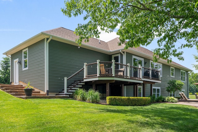 rear view of property with a deck, stairway, a yard, and roof with shingles