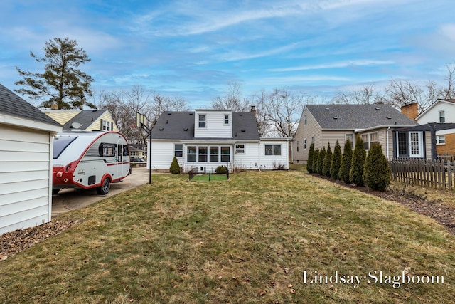 back of property featuring a lawn and fence