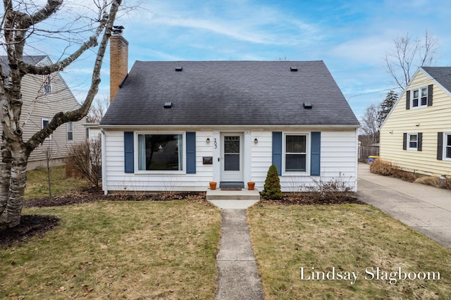 view of front of property with roof with shingles, a front lawn, and a chimney