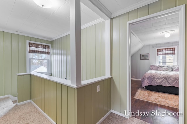 hallway featuring vaulted ceiling, carpet flooring, crown molding, and baseboards