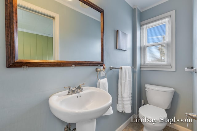 half bath featuring toilet, ornamental molding, and a sink