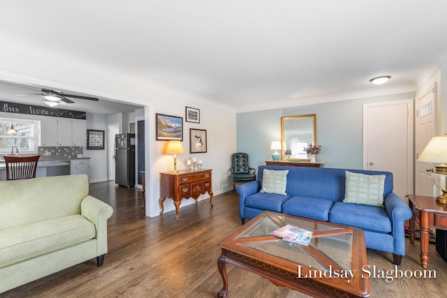 living area featuring baseboards, a ceiling fan, and wood finished floors