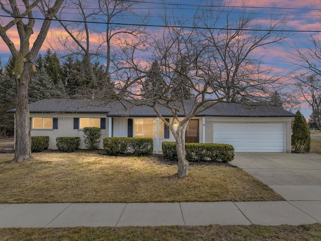 single story home with a garage, brick siding, concrete driveway, and a lawn