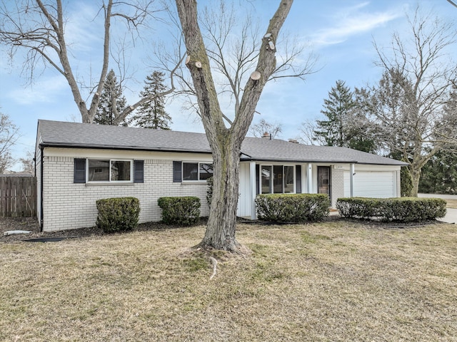 ranch-style house with fence, roof with shingles, a front yard, a garage, and brick siding