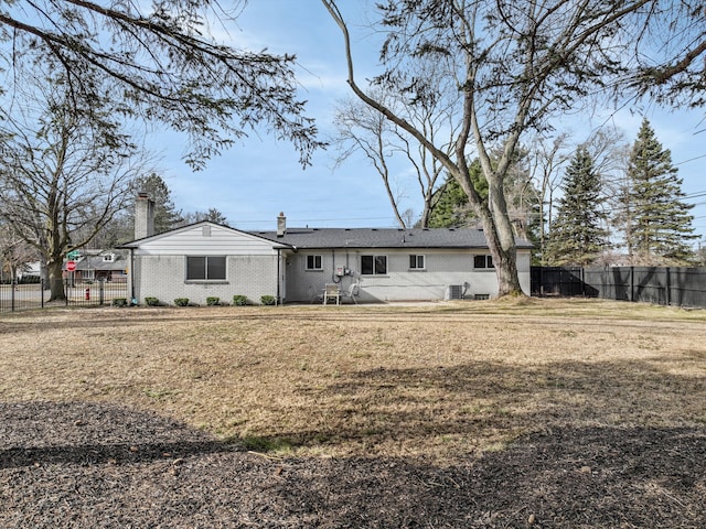 back of house featuring a chimney, a yard, and fence