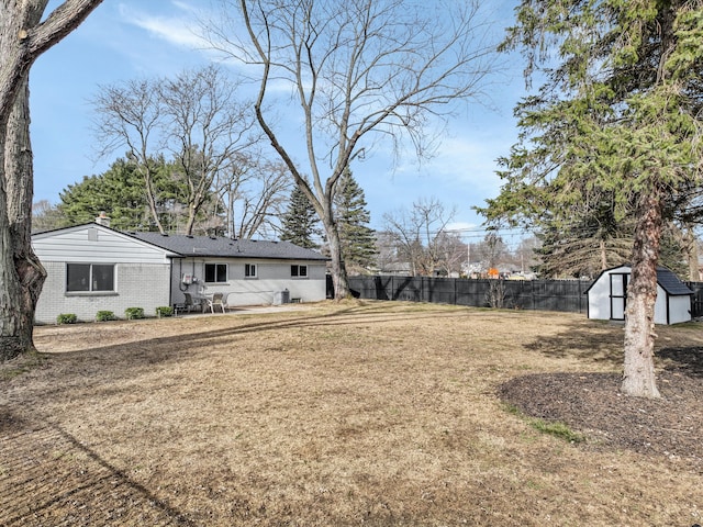 view of yard featuring a storage shed, fence, and an outbuilding