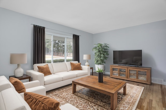 living room with light wood-type flooring, baseboards, and visible vents