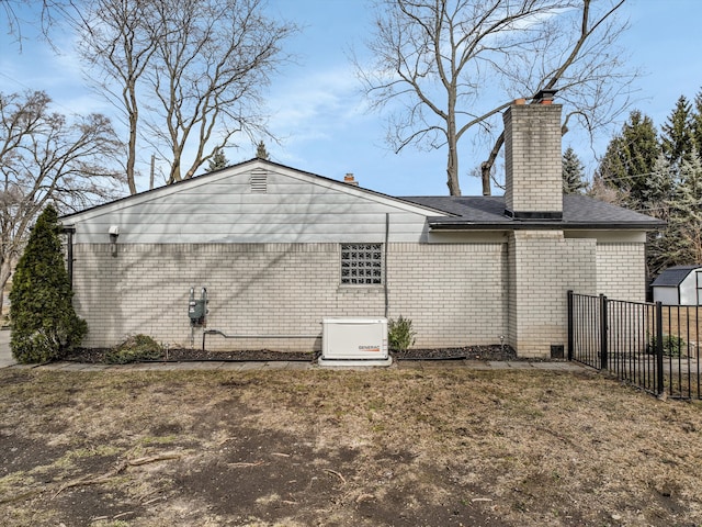 view of home's exterior with fence, brick siding, and a chimney