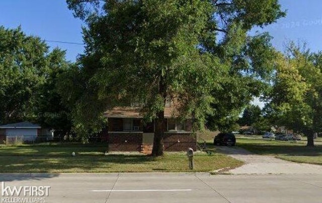 view of property hidden behind natural elements featuring a front lawn