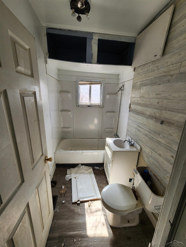 bathroom with shower / bathing tub combination, toilet, vanity, wooden walls, and wood finished floors