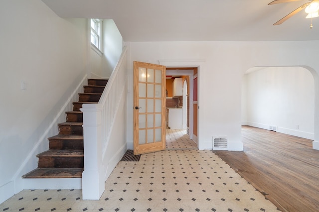 stairway featuring arched walkways, visible vents, ceiling fan, and wood finished floors