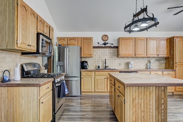 kitchen featuring dark wood-style floors, lofted ceiling, a sink, stainless steel appliances, and tile counters