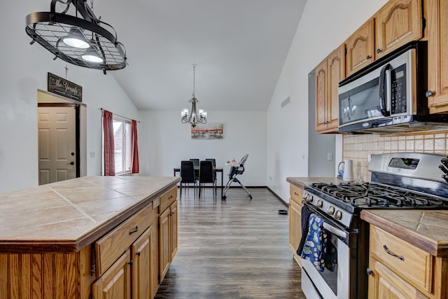 kitchen with decorative light fixtures, dark wood-style floors, stainless steel appliances, lofted ceiling, and tile counters