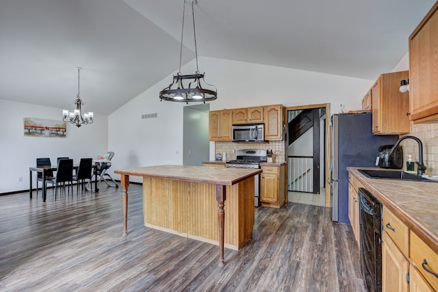 kitchen with tile countertops, dark wood-style floors, a sink, appliances with stainless steel finishes, and a kitchen bar