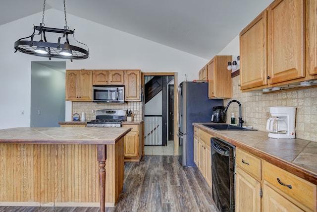 kitchen with a sink, dark wood finished floors, stainless steel appliances, tile counters, and vaulted ceiling