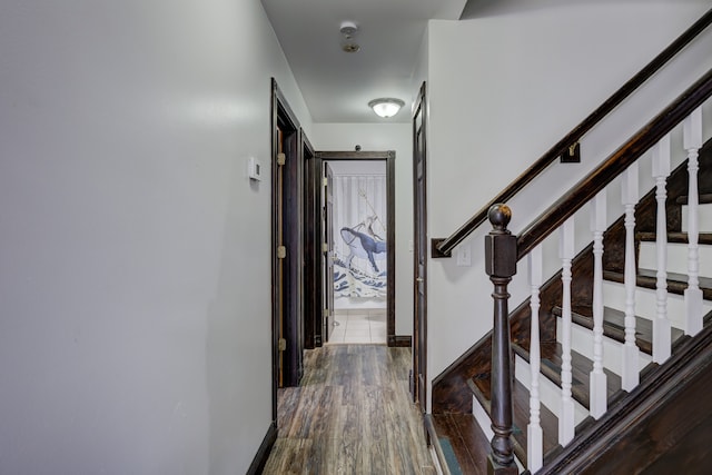 hallway featuring baseboards and dark wood-type flooring