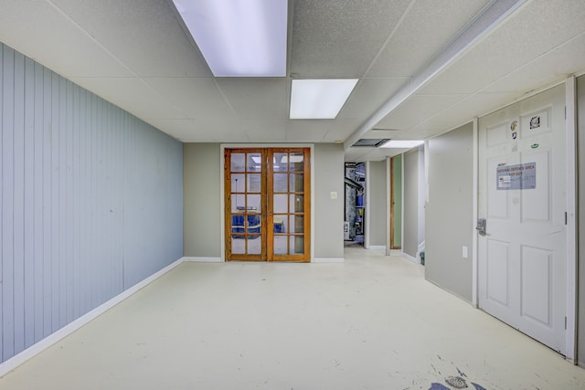 finished basement featuring french doors, a paneled ceiling, and baseboards