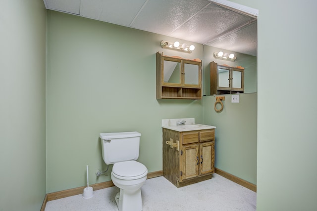 bathroom with speckled floor, toilet, vanity, and baseboards