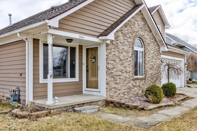 view of front of home featuring an attached garage, brick siding, driveway, and roof with shingles