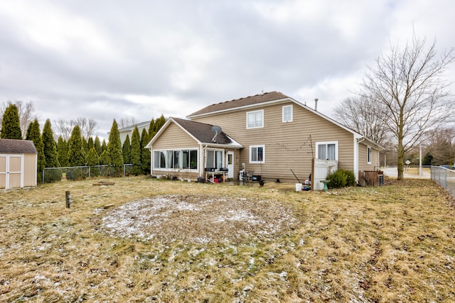 back of house with an outbuilding, a shed, a fenced backyard, and a sunroom