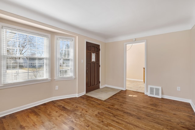 foyer with wood finished floors, visible vents, and baseboards