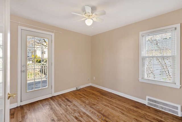 spare room with ceiling fan, wood finished floors, visible vents, and baseboards