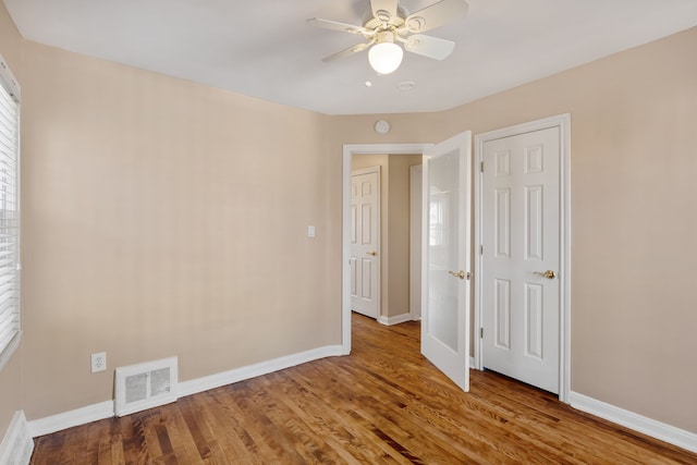 unfurnished bedroom with ceiling fan, visible vents, baseboards, and wood finished floors