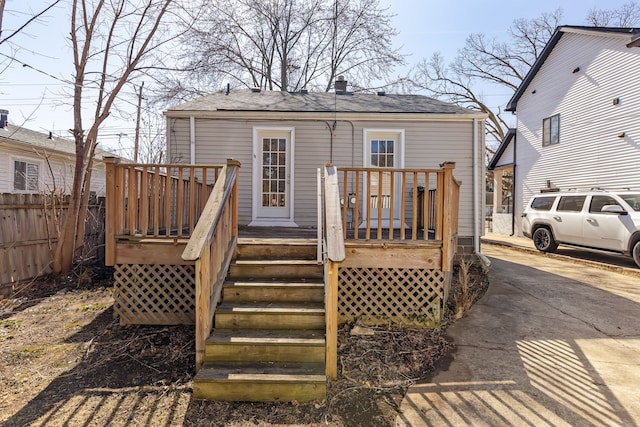 rear view of property with a deck, concrete driveway, stairs, and fence