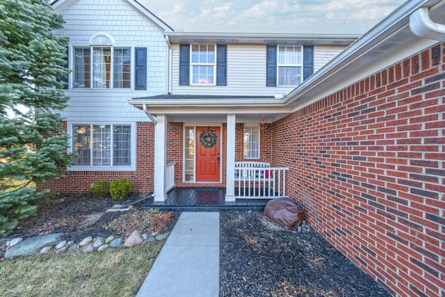 view of exterior entry with brick siding and covered porch