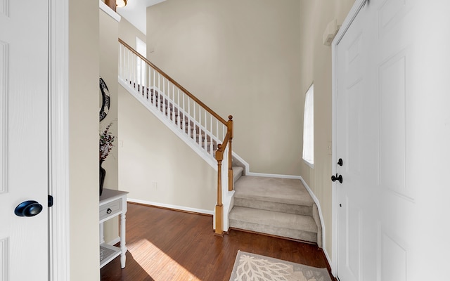 entrance foyer with stairs, a high ceiling, dark wood-style floors, and baseboards