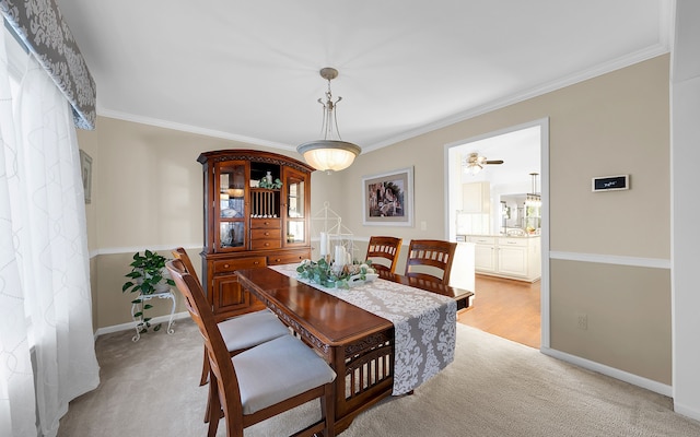 dining room featuring baseboards, light carpet, and crown molding