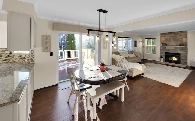 dining space with a stone fireplace, dark wood-type flooring, and ornamental molding