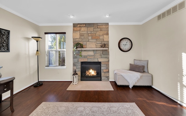 living area featuring wood finished floors, baseboards, visible vents, a fireplace, and ornamental molding