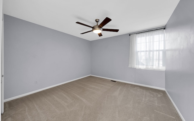 carpeted spare room featuring visible vents, ceiling fan, and baseboards