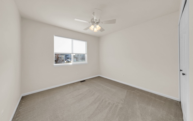 carpeted empty room featuring baseboards, visible vents, and ceiling fan