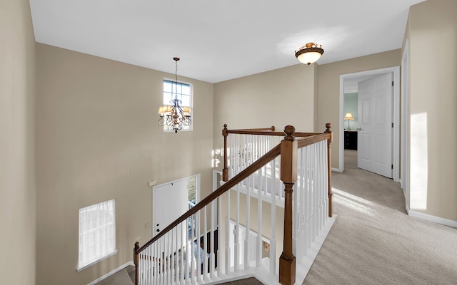 stairs featuring an inviting chandelier, carpet flooring, and baseboards