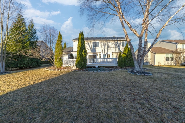 back of house featuring a lawn and a wooden deck